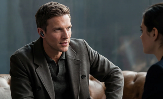 Business professional wearing soundcore noise cancelling earbuds during a call in a modern lounge.