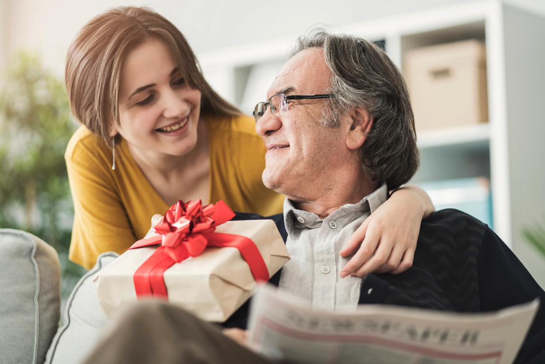 A daughter surprising her dad with a Father's Day gift while he relaxes at home.