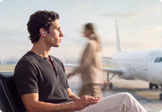 Anker soundcore Liberty Buds 2 bean-shaped earbuds worn by a traveler at an airport